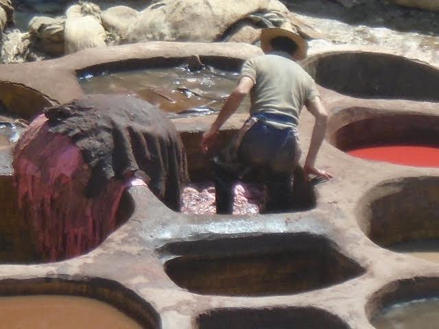 trabalhadores dentro do poço fazendo o tratamento do couro